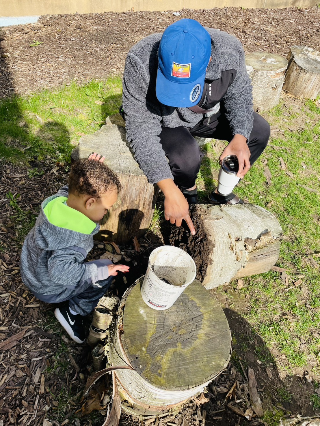 parent and child looking under a log together